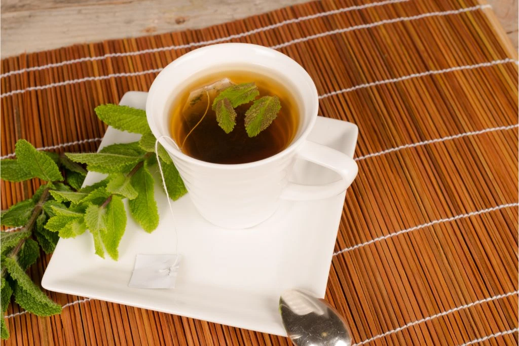 spearmint tea in a cup with spearmint leaves on a bamboo mat