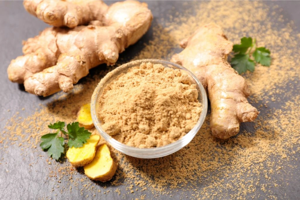 ginger root and ginger powder in a bowl on gray brackground