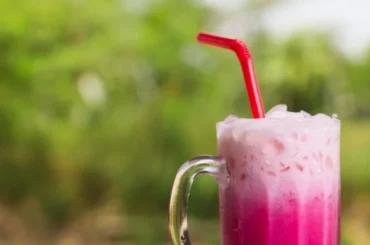 a glass of rose milk tea with a straw