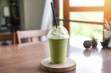 A cup on Avocado Milk tea with cream on top of a saucer