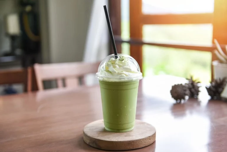 A cup on Avocado Milk tea with cream on top of a saucer