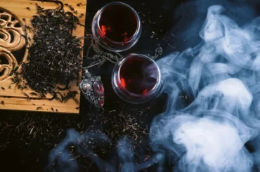 Two cups of tea with a pendant at the side on a black background