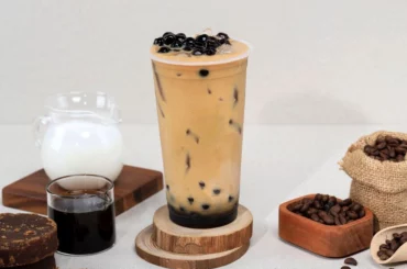 A coffee Milk tea in a cup with extra coffee and milk at the sides