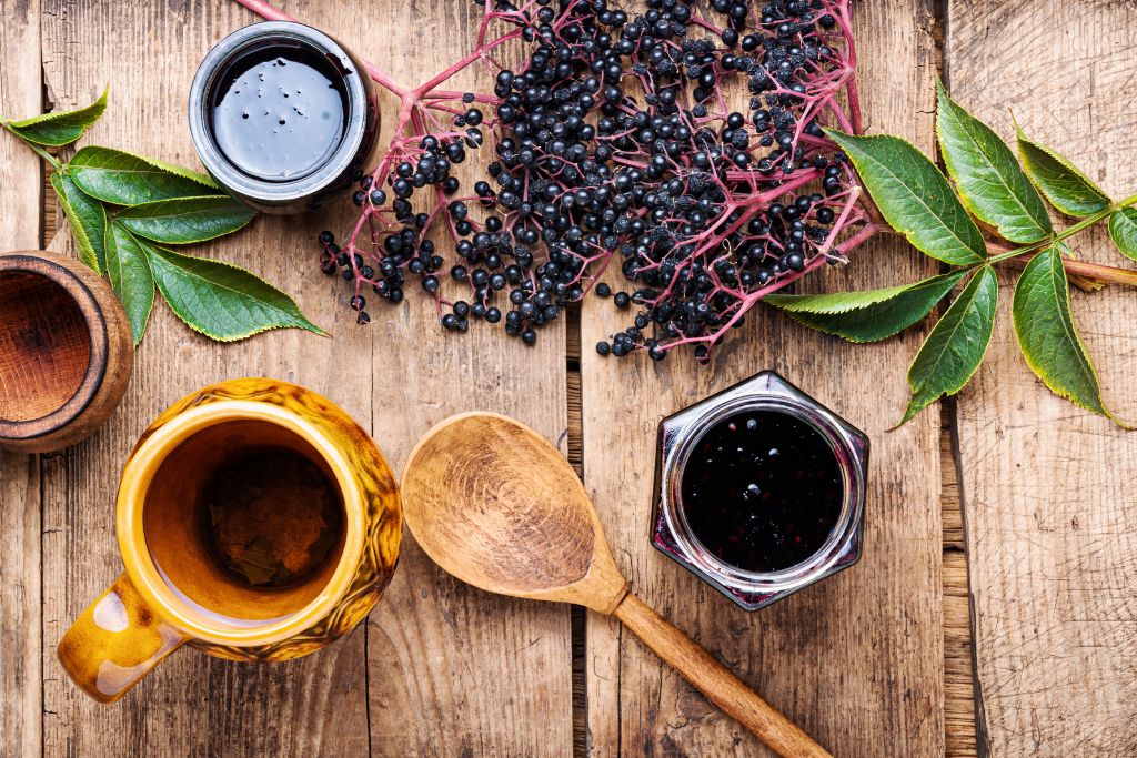 elderberries, cup and wooden spoon in a wooden table