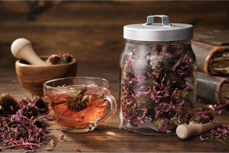 A jar with dried tea leaves and a tea cup with mortar and pestle on a table