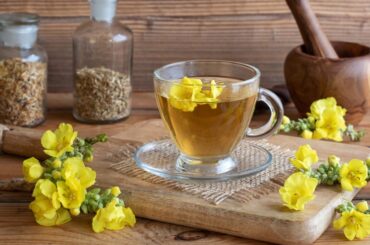 a cup of mullein tea with fresh mullein flowers on a rustic background