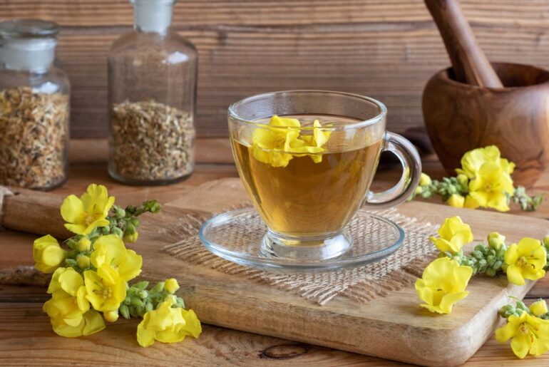 a cup of mullein tea with fresh mullein flowers on a rustic background