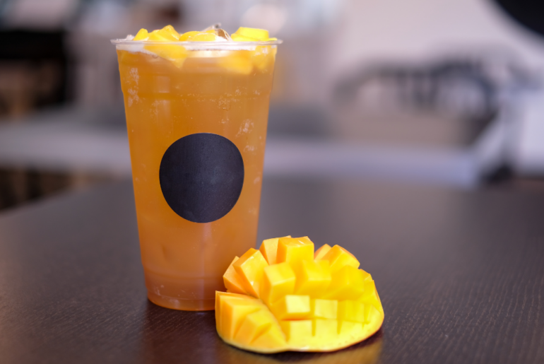 cold Mango black tea with mango chunks and a ripe mango slice