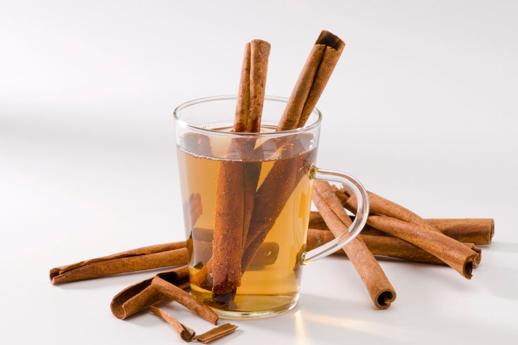 cinnamon sticks on small transparent glass situated on white table