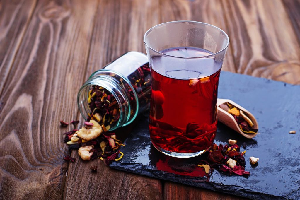 a glass of hibiscus tea with dried fruits and honey