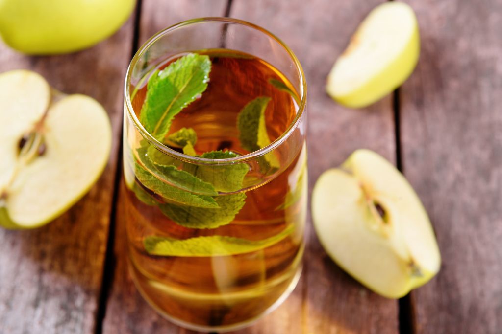 homemade apple mint tea together with scattered apple slices on table