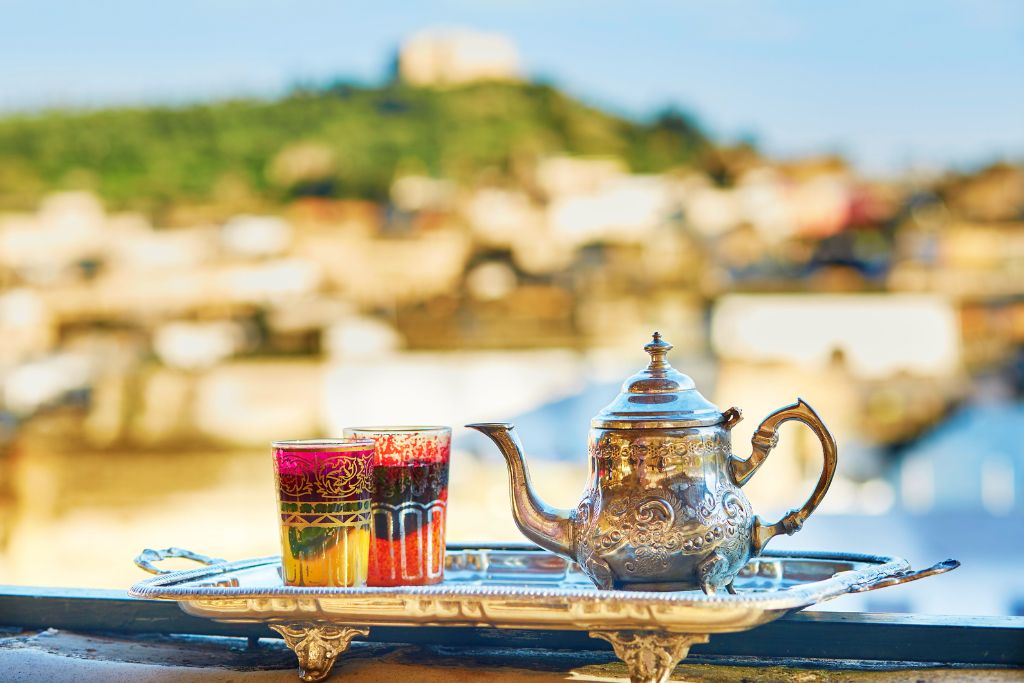 two glass of moroccan mint tea beside a silver kettle