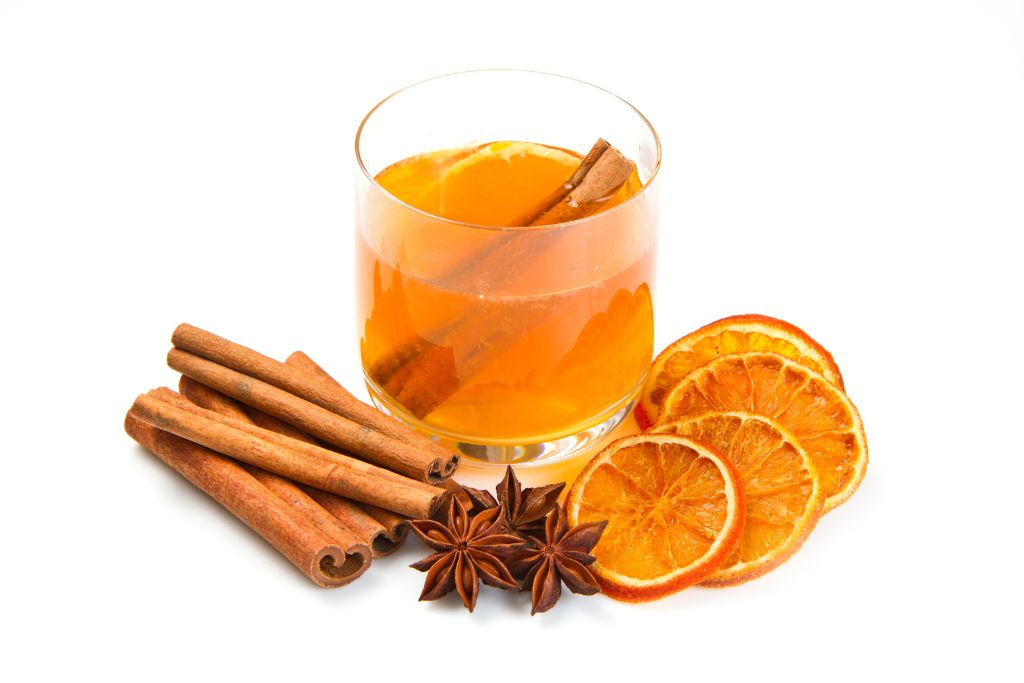 tea with oranges, cinnamon, and cloves on a white background