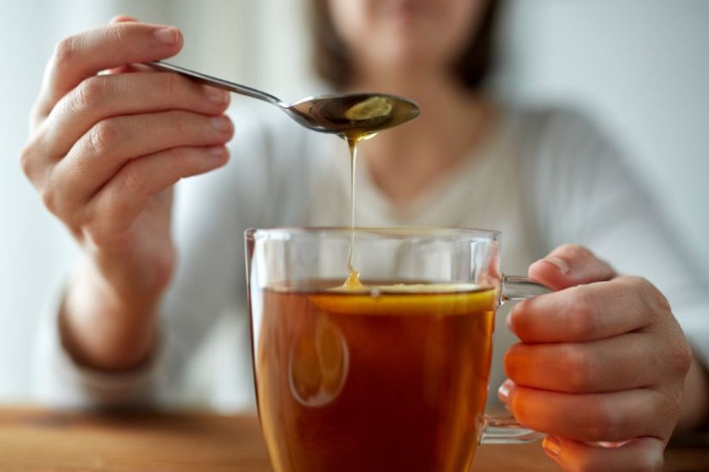 a woman holding a cup of honey citrus mint tea