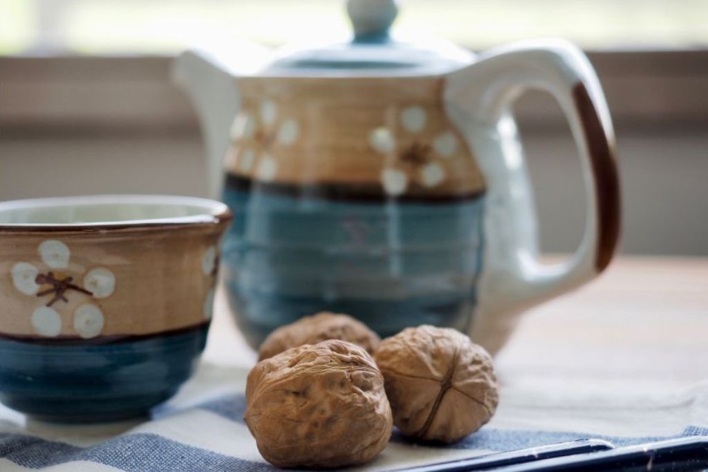 a cup and kettle with walnuts on the side